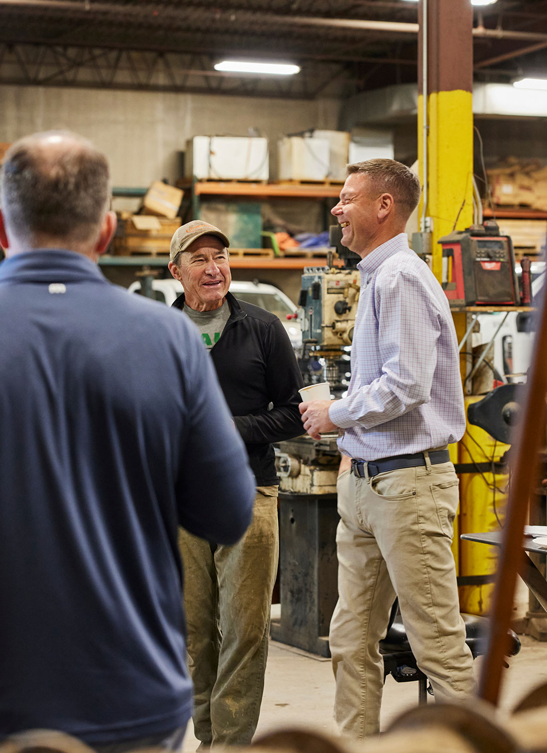 Three men in a warehouse space talking and laughing