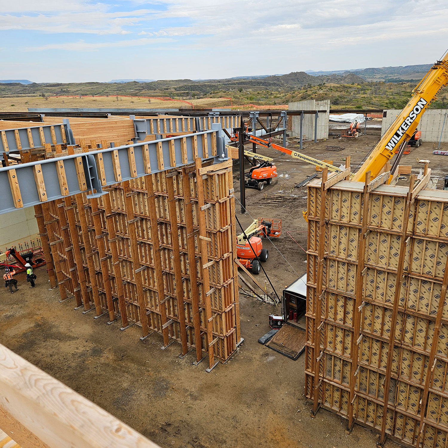 Work site with cranes and other heavy machinery with a hilly background.