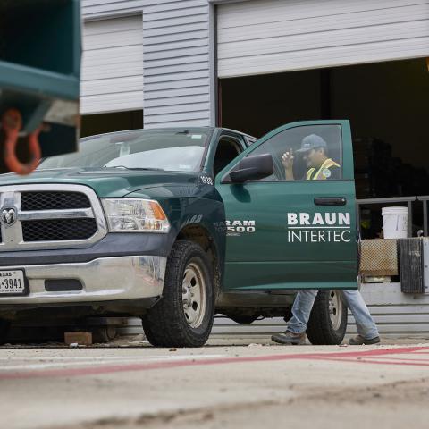Man in a safety vest getting into a pickup truck