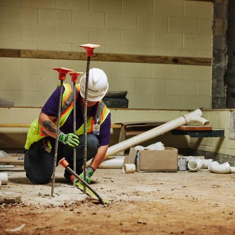 Man in PPE testing rebar on a work site