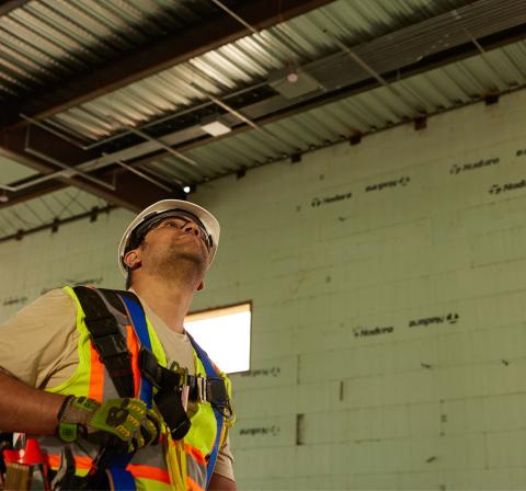 Worker in hard hat and safety vest looking at ceiling