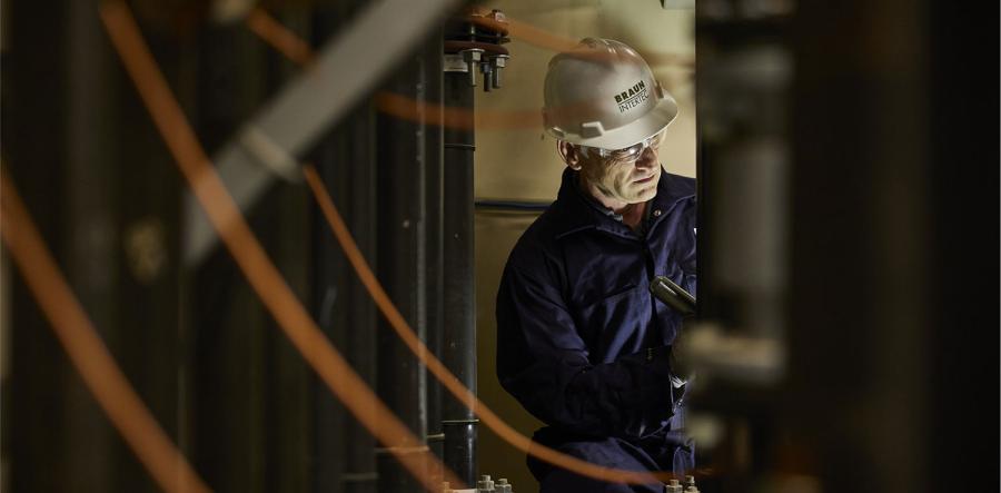 Man in a hard hat and jumpsuit working in a basement