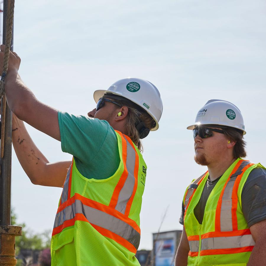 Two men in PPE using a drill rig