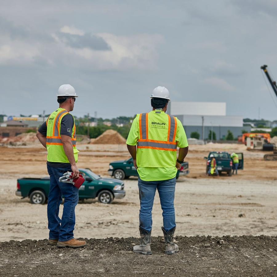 Two people in PPE overseeing a site